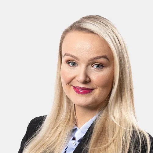 Kona með ljóst hár og jakkaföt brosandi